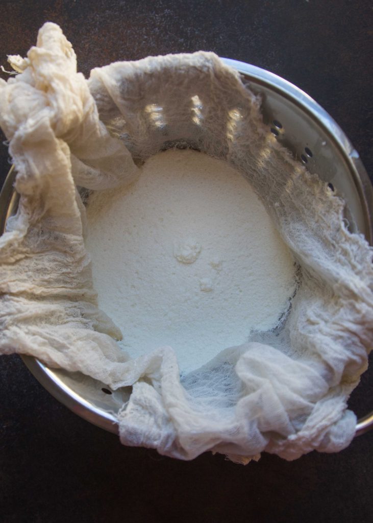 Fresh ricotta made from scratch in a cheesecloth-lined colander.