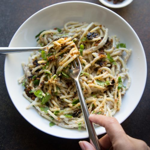 Hands twirling spaghetti in almond cream sauce with pockets of fiery cauliflower make this a keepsake addition to your vegan cauliflower recipes.
