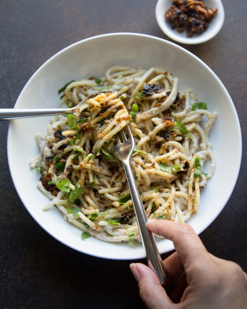 Hands twirling spaghetti in almond cream sauce with pockets of fiery cauliflower make this a keepsake addition to your vegan cauliflower recipes.